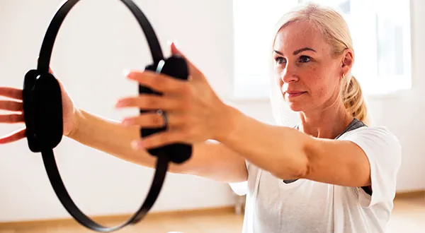 Mujer madura realizando un ejercicio de Pilates Mat con aro mágico