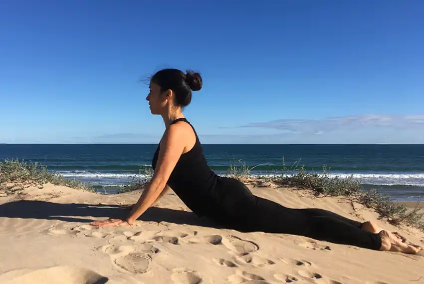 Fátima Pastor ejecutando el ejercicio de Pilates Mat en la playa
