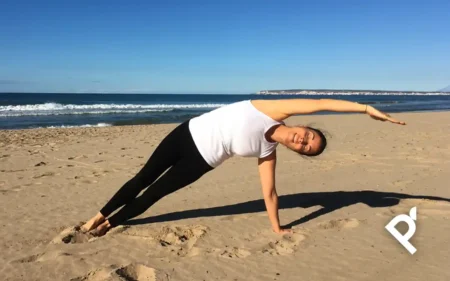 Ejecución del ejercicio de Pilates Side Bend por parte de Fátima Pastor Andreu en la playa