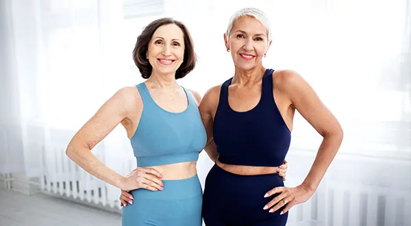 Dos mujeres abrazadas sonrientes en un descanso de una clase de Pilates Mat